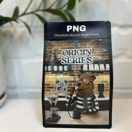 Medium roast coffee beans from Okapa Papua New Guinea in a bag, described as tasting like chocolate biscuit with gentle tropical fruit notes, comforting and well balanced.